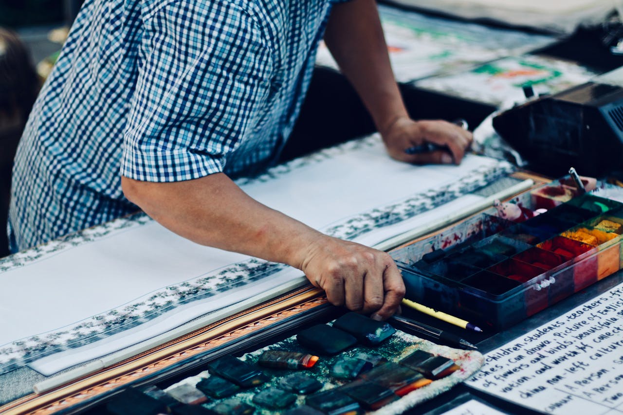 Close-up of a person painting with watercolors, focusing on creativity in an indoor setting.