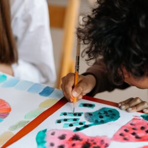 A child joyfully paints watermelon patterns, exploring creativity through art.