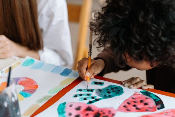 A child joyfully paints watermelon patterns, exploring creativity through art.